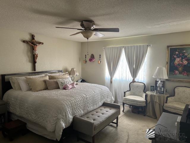 carpeted bedroom with ceiling fan and a textured ceiling