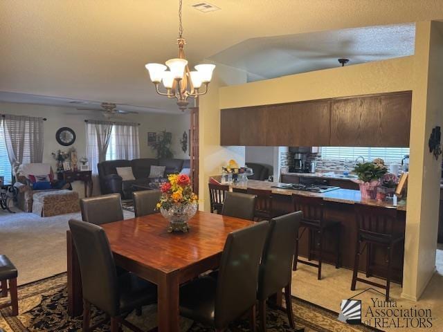 carpeted dining space with ceiling fan with notable chandelier and lofted ceiling