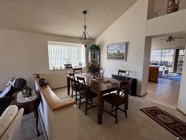 dining room featuring ceiling fan, high vaulted ceiling, light tile patterned floors, and a textured ceiling