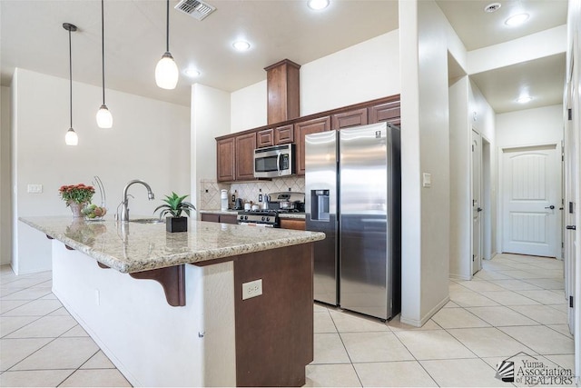 kitchen with light tile patterned floors, stainless steel appliances, a sink, visible vents, and decorative backsplash