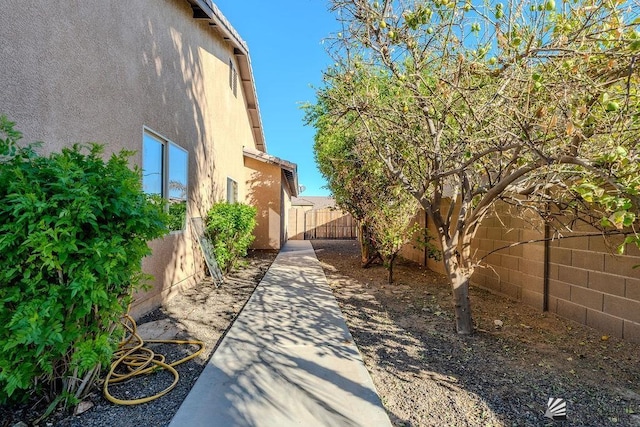 view of side of home featuring a fenced backyard and stucco siding