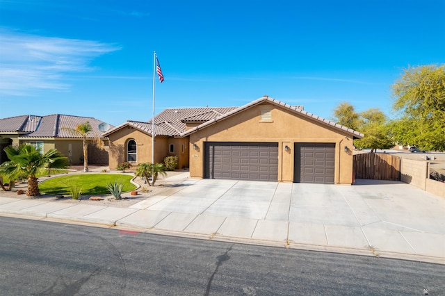 mediterranean / spanish home with a garage, a tile roof, fence, driveway, and stucco siding