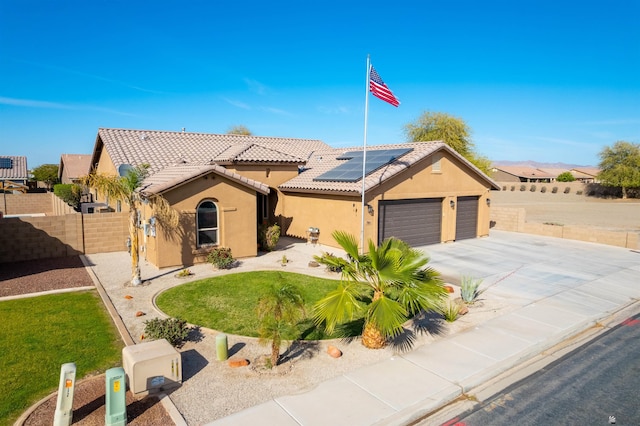 view of front of home with a tile roof, an attached garage, fence, roof mounted solar panels, and stucco siding