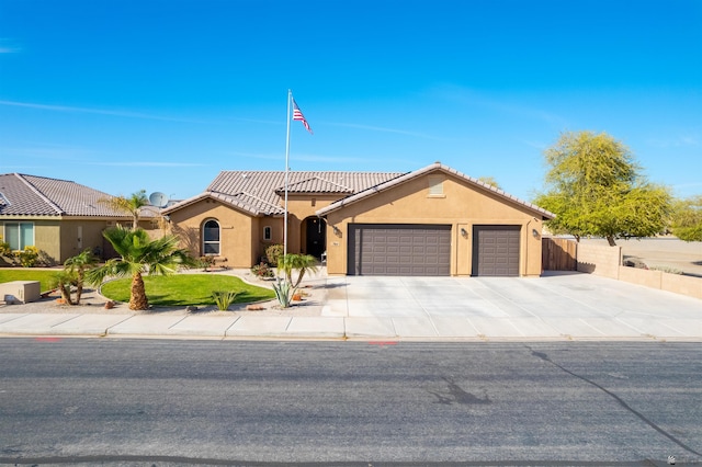 mediterranean / spanish home with stucco siding, fence, a garage, driveway, and a front lawn