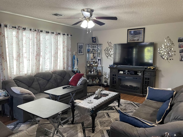 living room with ceiling fan, hardwood / wood-style floors, and a textured ceiling