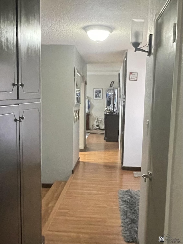 hall with wood-type flooring and a textured ceiling