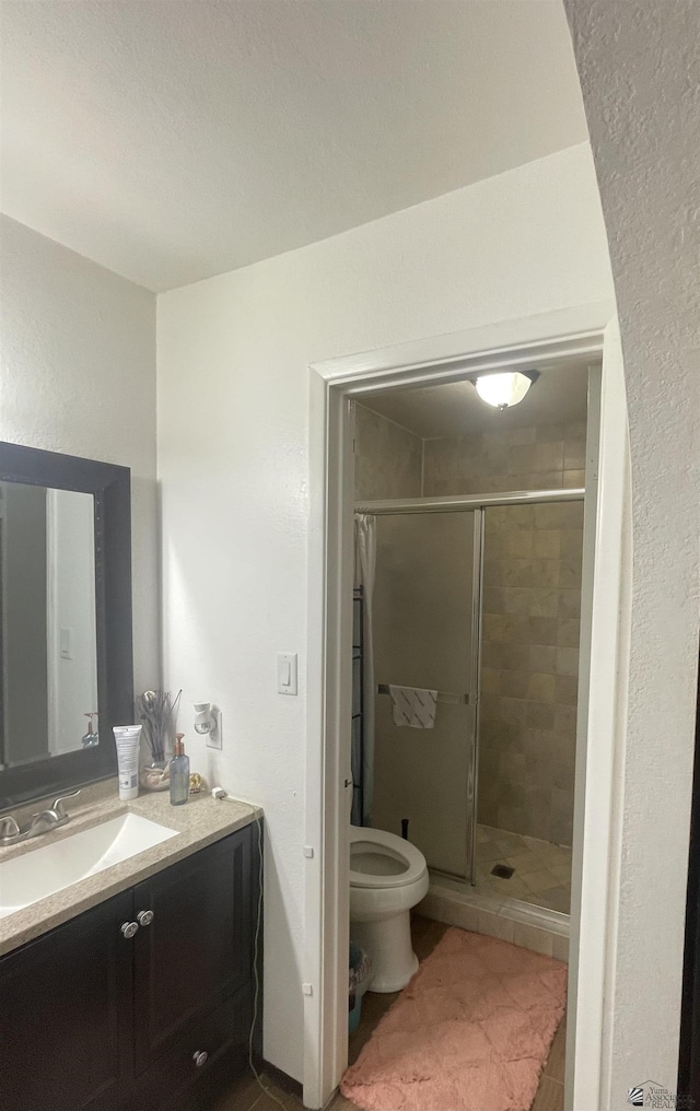 bathroom with tile patterned flooring, vanity, toilet, and a shower with shower door