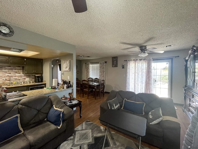 living room featuring ceiling fan, sink, hardwood / wood-style floors, and a textured ceiling