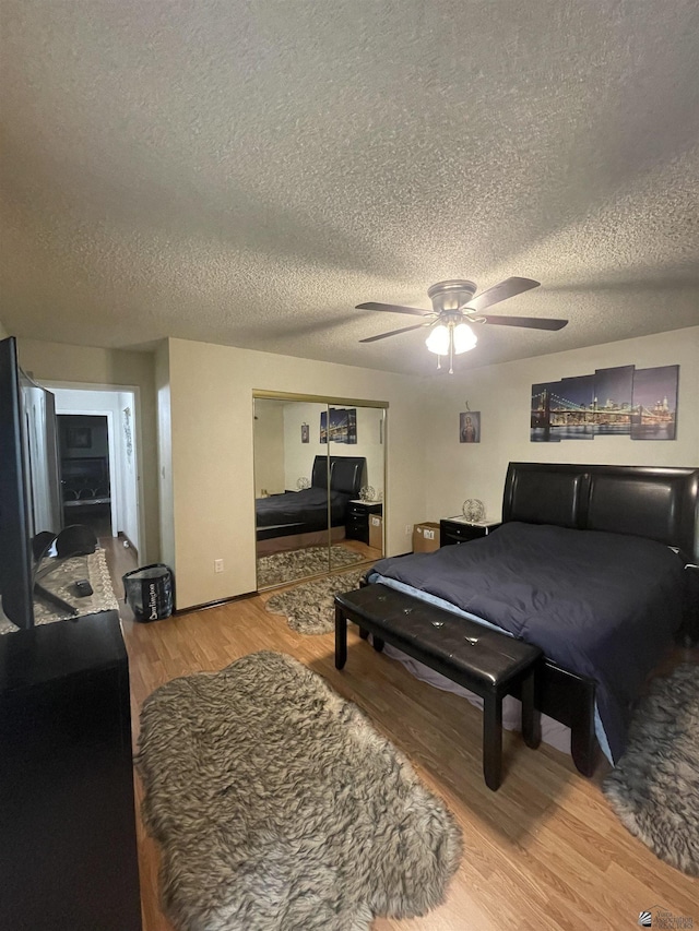 bedroom featuring hardwood / wood-style floors, a textured ceiling, ceiling fan, and a closet