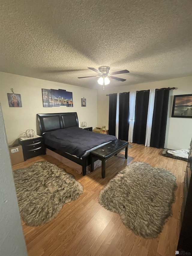 bedroom featuring ceiling fan, a textured ceiling, and light wood-type flooring