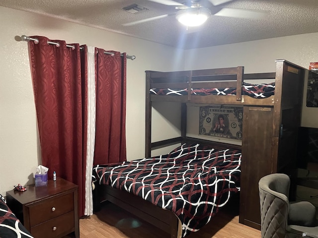 bedroom featuring ceiling fan, light hardwood / wood-style floors, and a textured ceiling