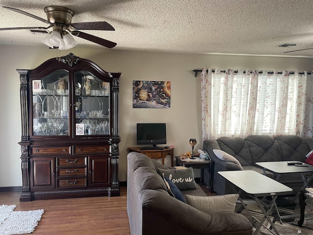 living room with a textured ceiling, dark hardwood / wood-style floors, and ceiling fan