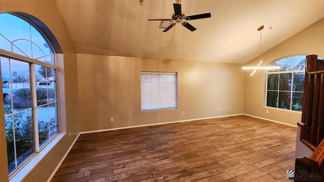 spare room featuring lofted ceiling, ceiling fan with notable chandelier, wood finished floors, and a healthy amount of sunlight