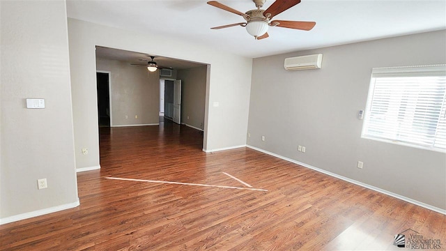 spare room featuring ceiling fan, baseboards, wood finished floors, and a wall mounted air conditioner