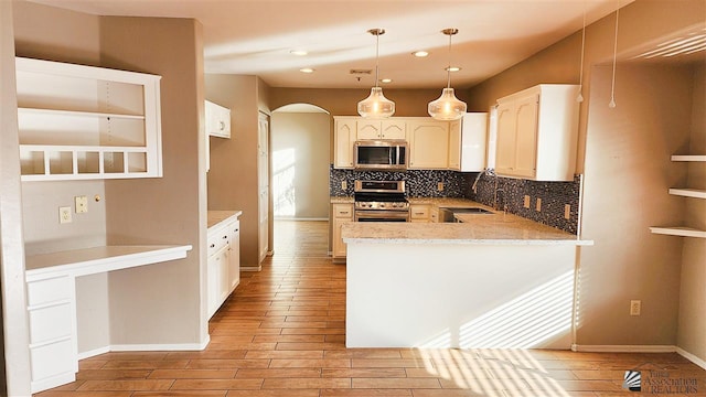 kitchen with tasteful backsplash, arched walkways, a peninsula, stainless steel appliances, and a sink