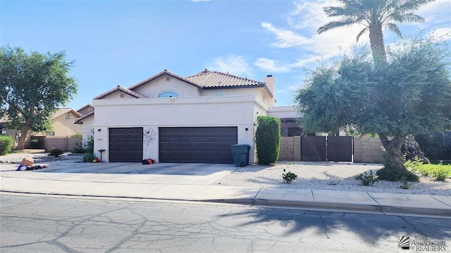 mediterranean / spanish-style home featuring driveway, a garage, a chimney, fence, and stucco siding