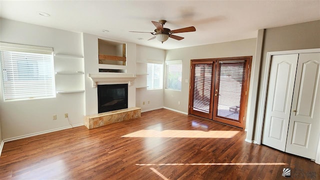 unfurnished living room featuring baseboards, wood finished floors, and a glass covered fireplace