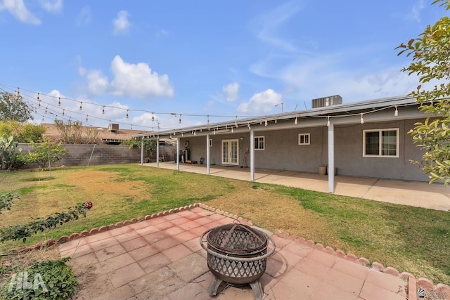 back of property with a patio area, an outdoor fire pit, a lawn, and stucco siding