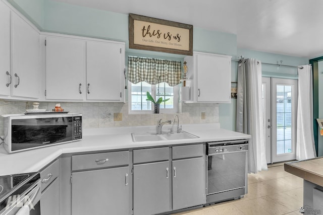 kitchen with stainless steel appliances, a sink, white cabinets, light countertops, and tasteful backsplash