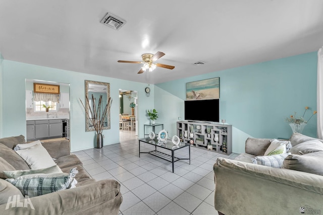 living room with light tile patterned floors, visible vents, and a ceiling fan