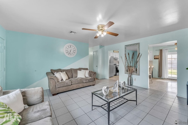 living room with ceiling fan, visible vents, and light tile patterned flooring