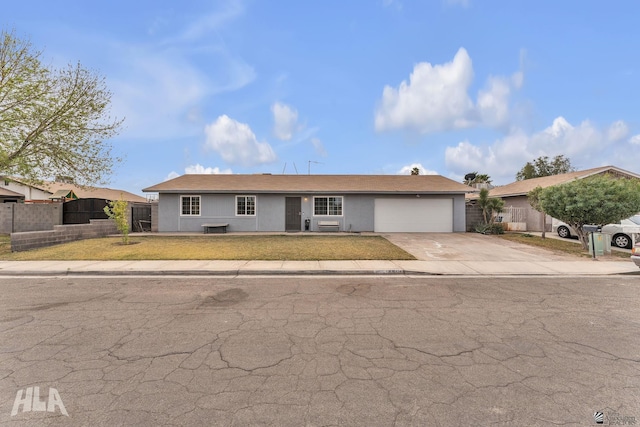 ranch-style house featuring driveway, an attached garage, fence, and stucco siding