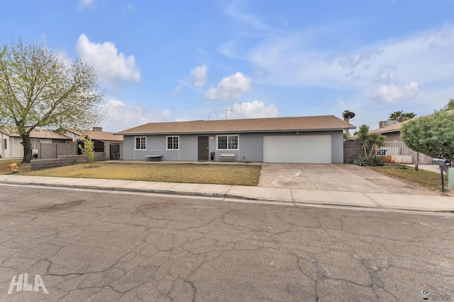 ranch-style house with concrete driveway, an attached garage, fence, a front yard, and stucco siding