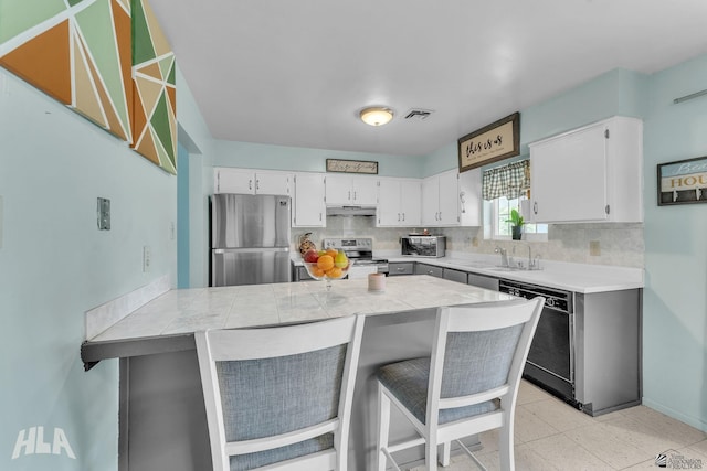 kitchen with tasteful backsplash, visible vents, white cabinets, stainless steel appliances, and a kitchen bar