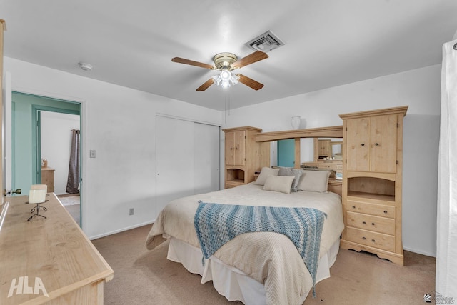 bedroom with ceiling fan, visible vents, a closet, and light colored carpet