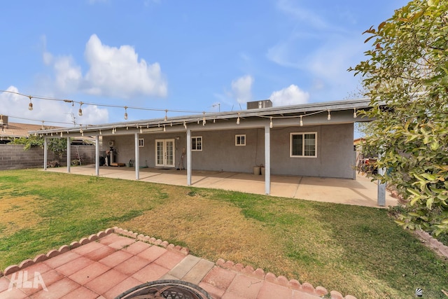 back of house featuring french doors, a patio area, a yard, and stucco siding