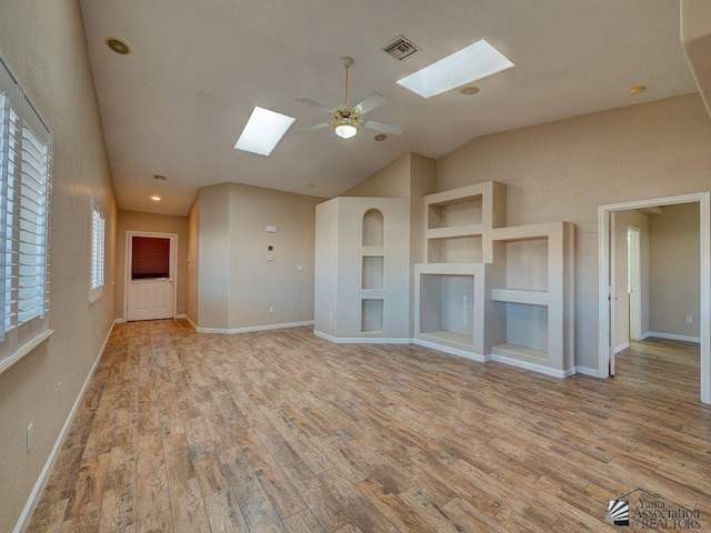 unfurnished living room with ceiling fan, lofted ceiling with skylight, light hardwood / wood-style floors, and built in features