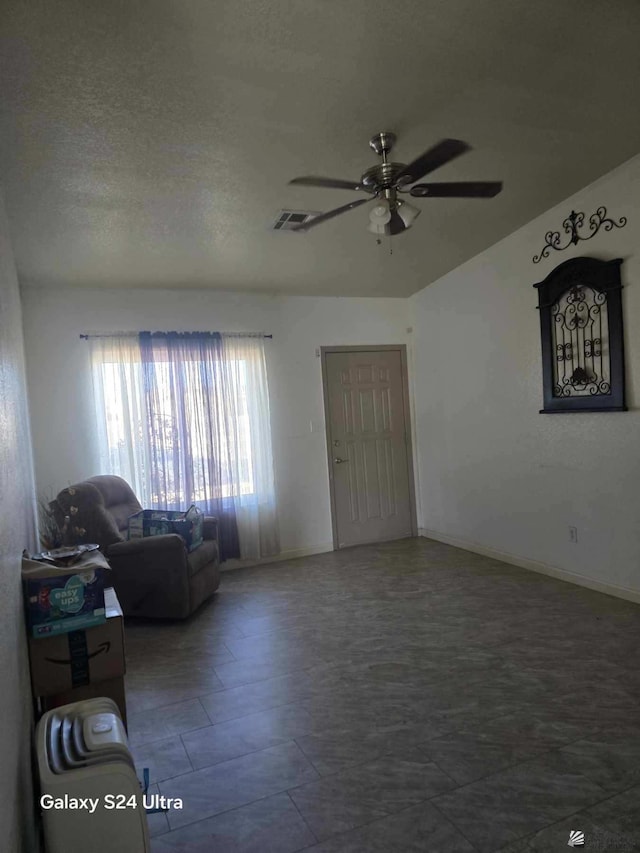 living room featuring a textured ceiling and ceiling fan