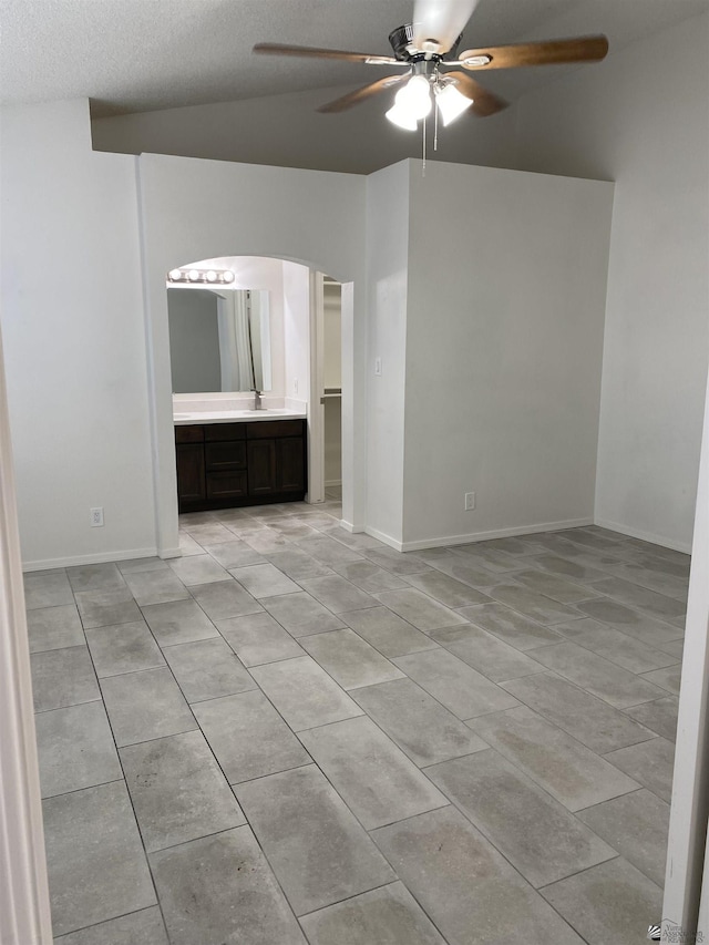 empty room featuring a textured ceiling, ceiling fan, and lofted ceiling