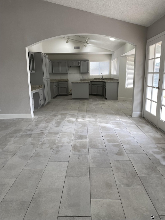 kitchen featuring gray cabinets, a wealth of natural light, light tile patterned floors, and a textured ceiling