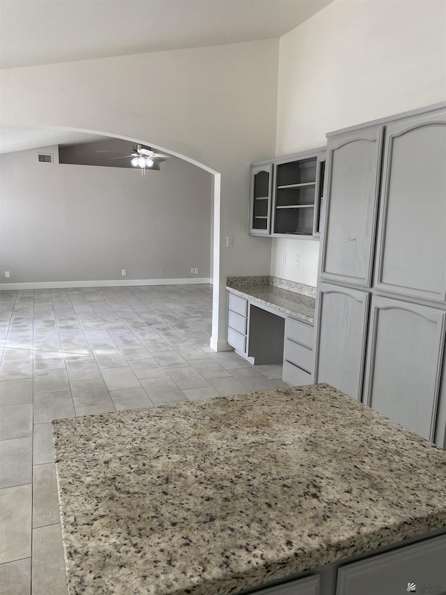 kitchen featuring gray cabinetry, ceiling fan, built in desk, and lofted ceiling