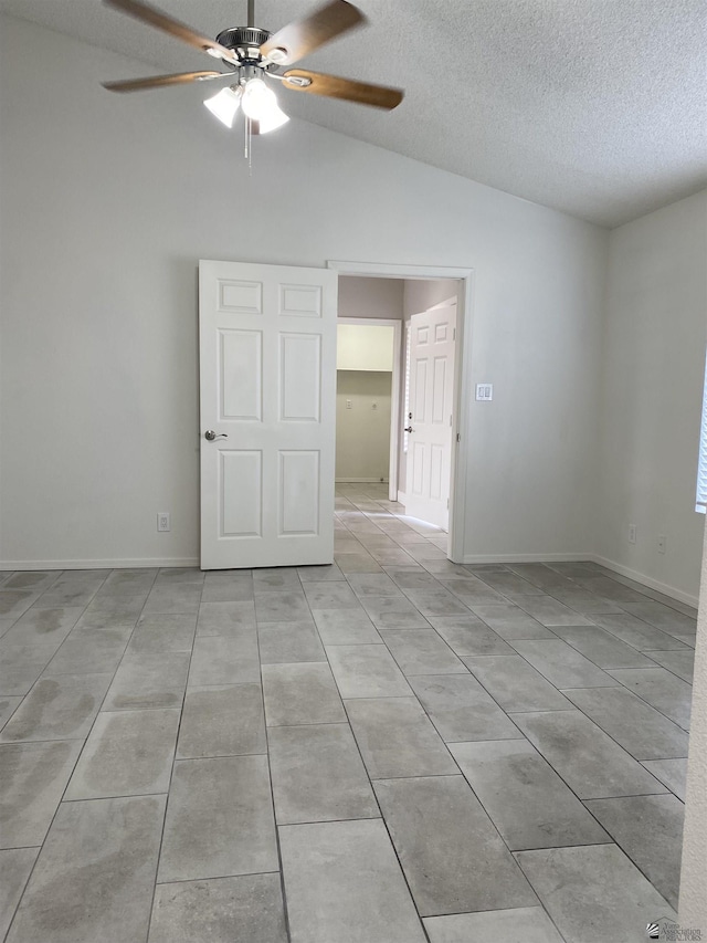 tiled spare room with a textured ceiling, ceiling fan, and vaulted ceiling