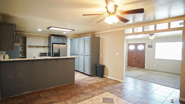 kitchen with gray cabinets, kitchen peninsula, ornamental molding, and appliances with stainless steel finishes