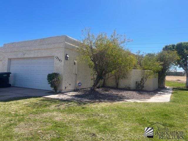 view of home's exterior featuring concrete driveway, a lawn, an attached garage, and stucco siding