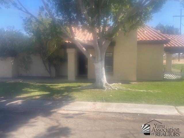 view of home's exterior featuring stucco siding, a tile roof, and a yard