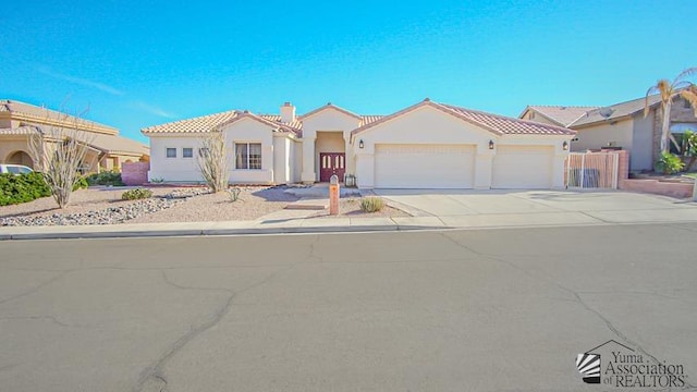 mediterranean / spanish home with a tiled roof, a garage, concrete driveway, and stucco siding