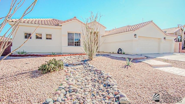 mediterranean / spanish home with a tile roof, stucco siding, an attached garage, and concrete driveway