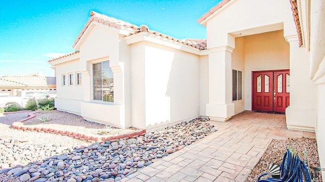 view of side of home featuring a tile roof and stucco siding