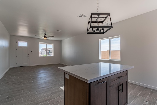 kitchen with ceiling fan, a kitchen island, and hanging light fixtures