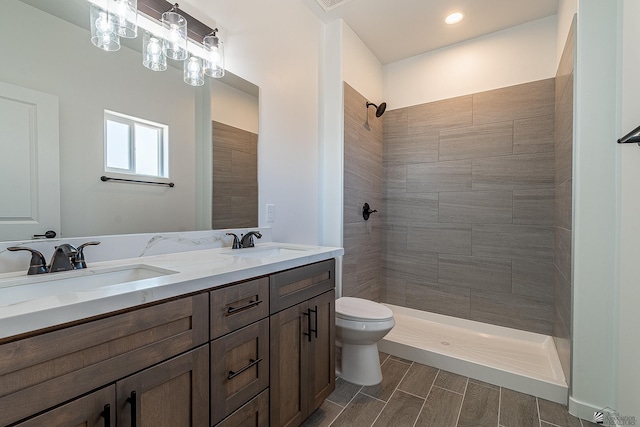 bathroom with a tile shower, vanity, and toilet