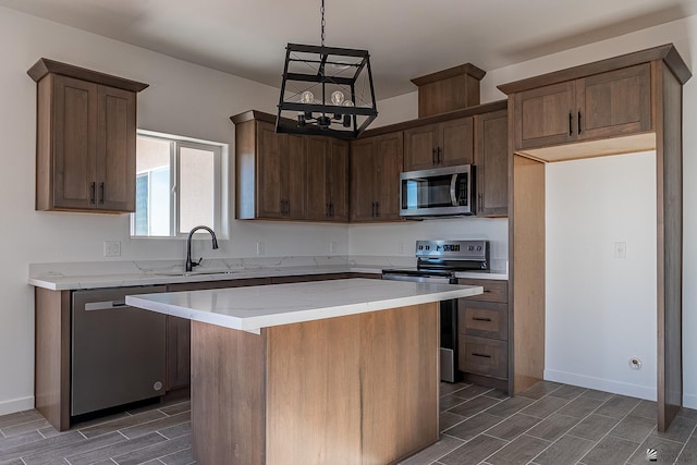 kitchen with a kitchen island, sink, stainless steel appliances, and hanging light fixtures