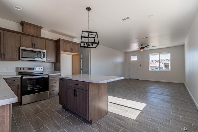 kitchen with pendant lighting, ceiling fan, a kitchen island, and stainless steel appliances