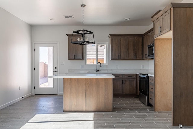 kitchen featuring sink, a kitchen island, hanging light fixtures, and black appliances