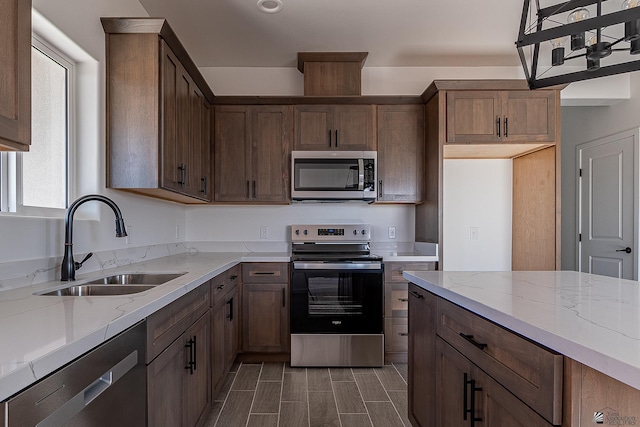 kitchen featuring light stone countertops, sink, pendant lighting, and appliances with stainless steel finishes