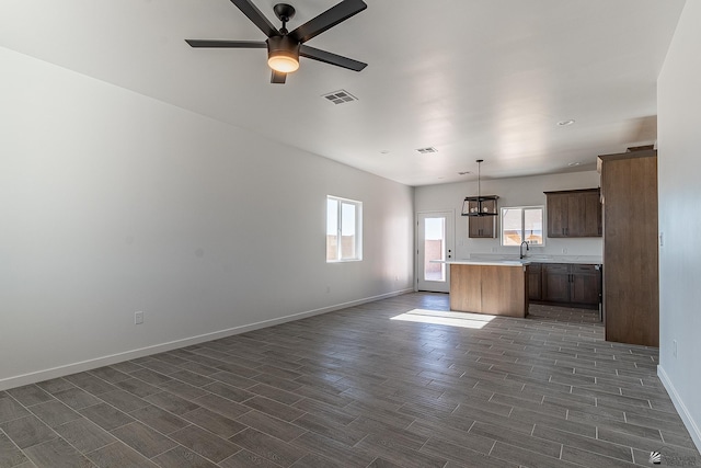 kitchen with sink, a kitchen island, pendant lighting, and ceiling fan with notable chandelier