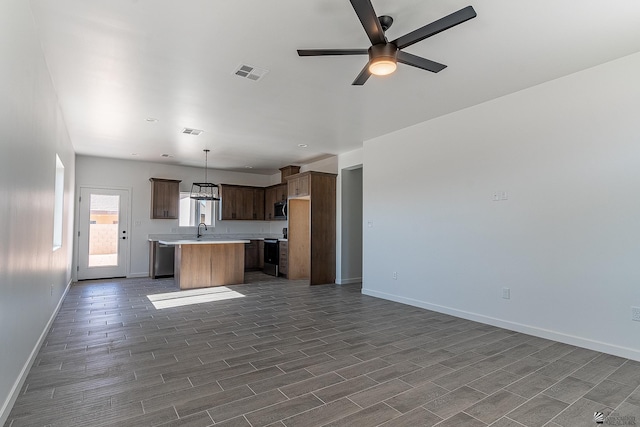 kitchen with appliances with stainless steel finishes, ceiling fan, sink, decorative light fixtures, and a kitchen island